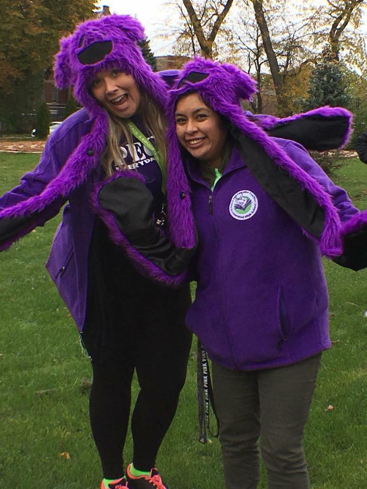 two women in fuzzy purple hats doing a goofy pose for the camera